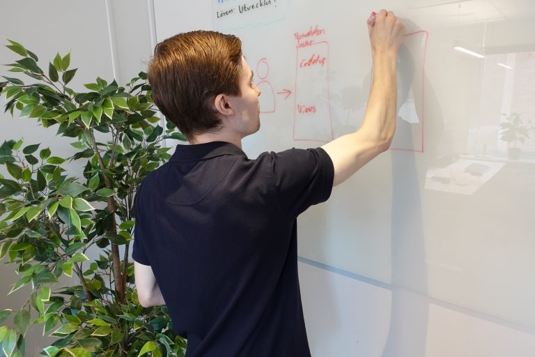 Gustav Persson ritar ett diagram på en whiteboard hos Albia Sweden AB